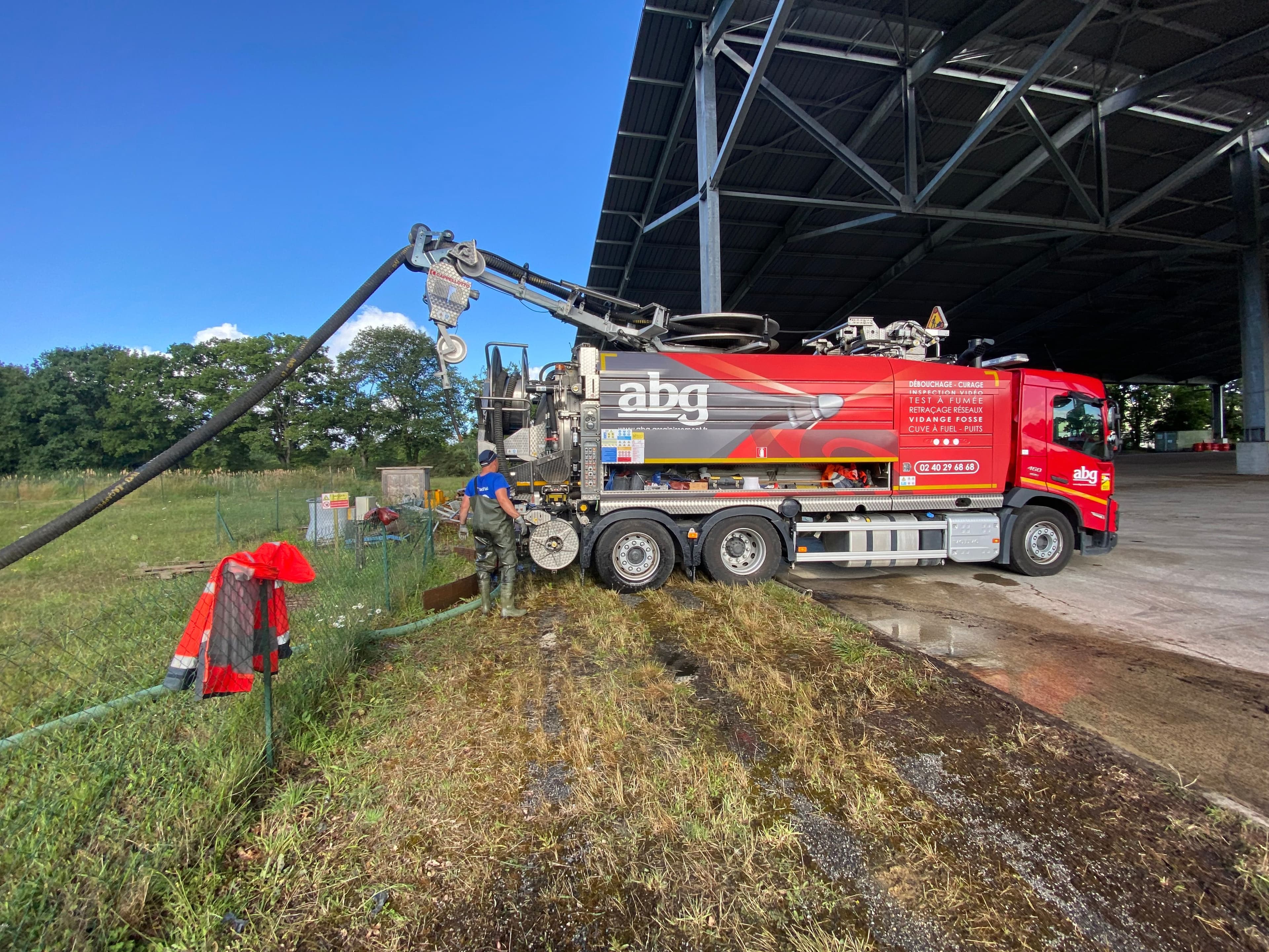 Camion hydrocureur ABG effectuant une vidange de fosse sur un site industriel en Loire Atlantique, technicien en action.